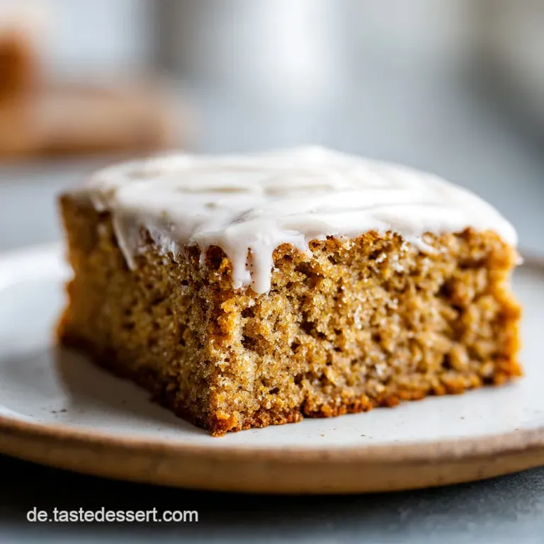 Slice of moist spice cake with a delicate dusting of confectioner's sugar on a plate, hints of warm spices are visible.