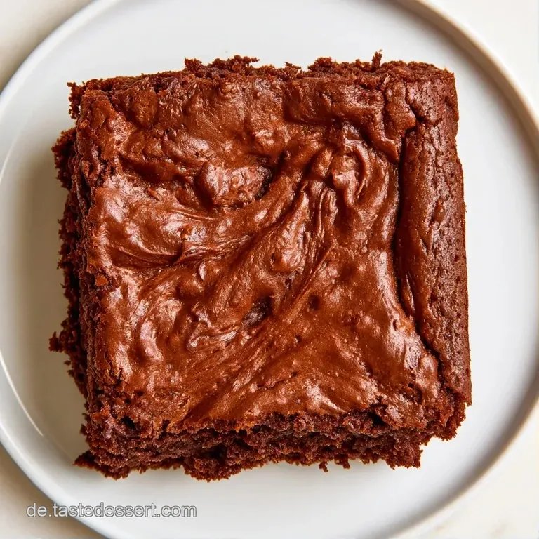 Ein quadratisches St&uuml;ck dunkles Kuchengeb&auml;ck auf einem wei&szlig;en Teller, garniert mit einer frischen, roten Himbeere.